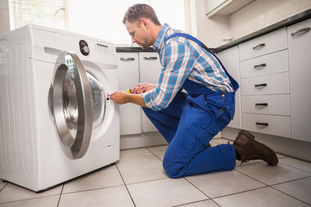 33949789 handyman fixing a washing machine in the kitchen